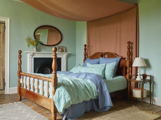 A mint green bedroom with terracotta sheet overhanging the bed