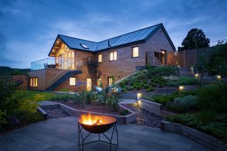 self build with tiered patio garden with fire pit