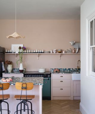 light plaster pink kitchen with island unit, parquet flooring and green cooker