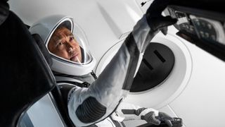 koichi wakata astronaut reaching for a spacecraft panel in a white spacesuit