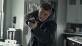 Gabriel Basso pointing his gun forward as he walks through a house in The Night Agent Season 3