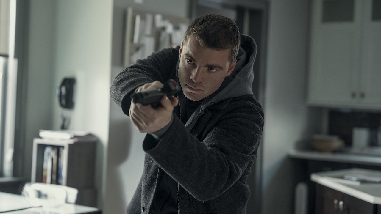 Gabriel Basso pointing his gun forward as he walks through a house in The Night Agent Season 3
