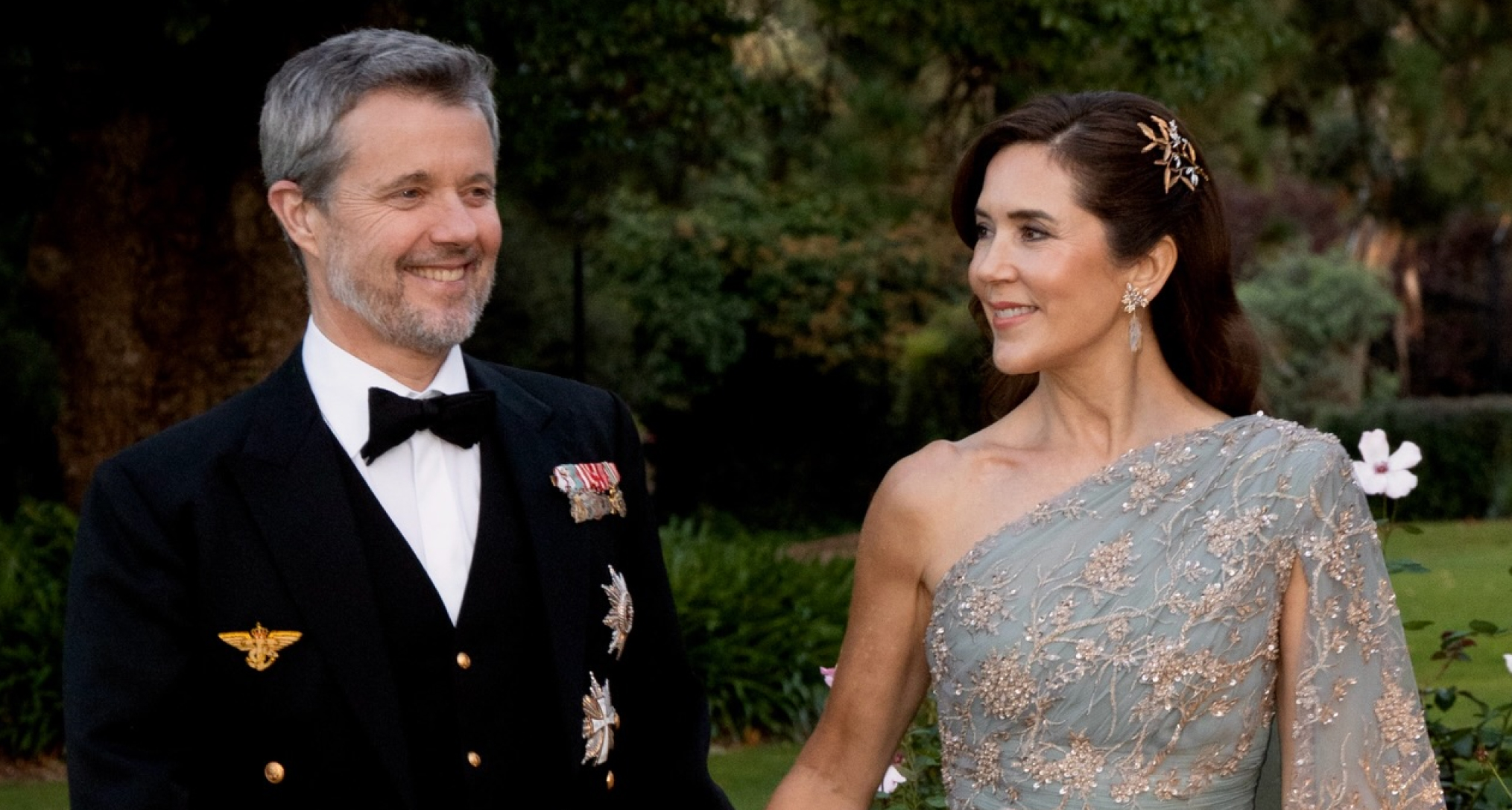 Queen Mary in a mint gown holding hands with King Frederik 