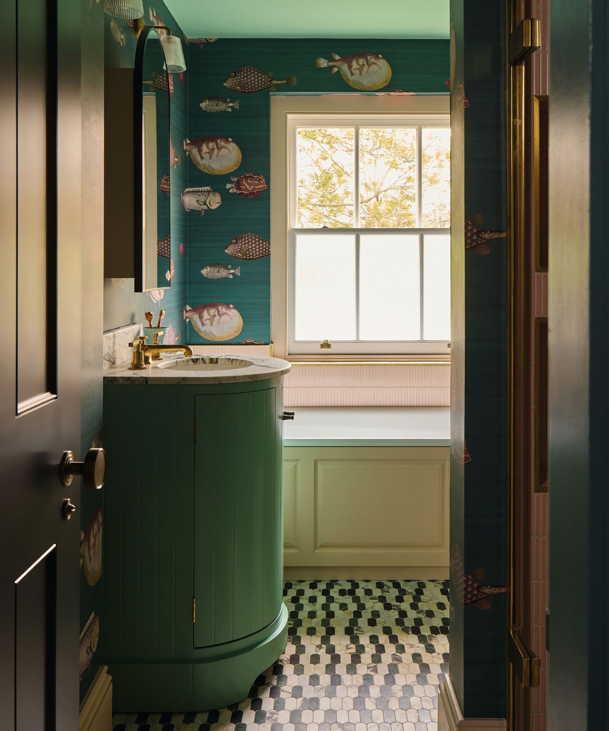 a green and blue bathroom with fish wallpaper, soft yellow bath panel, mosaic tiled floor and a bright green curved vanity sink