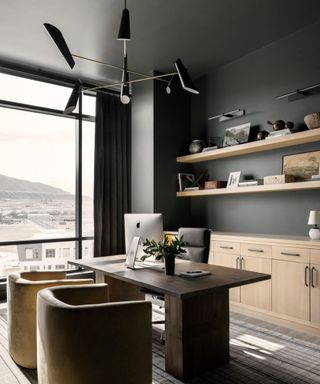 An office with dark gray walls and wooden floating shelves