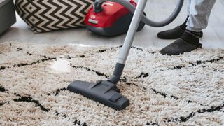 Man showing how to clean a rug at home using a vacuum cleaner.
