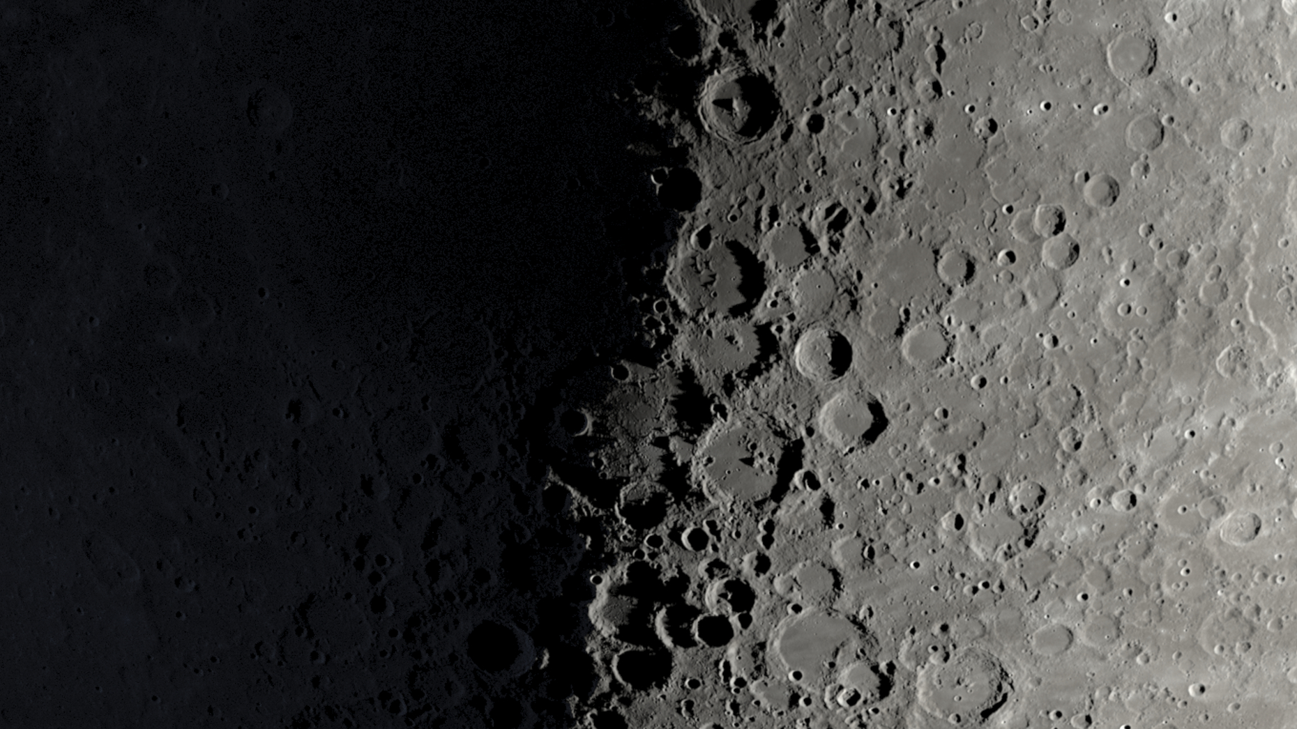A NASA graphic showing a part of the moon's surface around its first quarter phase when its right half is lit by the sun and its left is in shadow. Large craters can be seen lining the night-day divide.