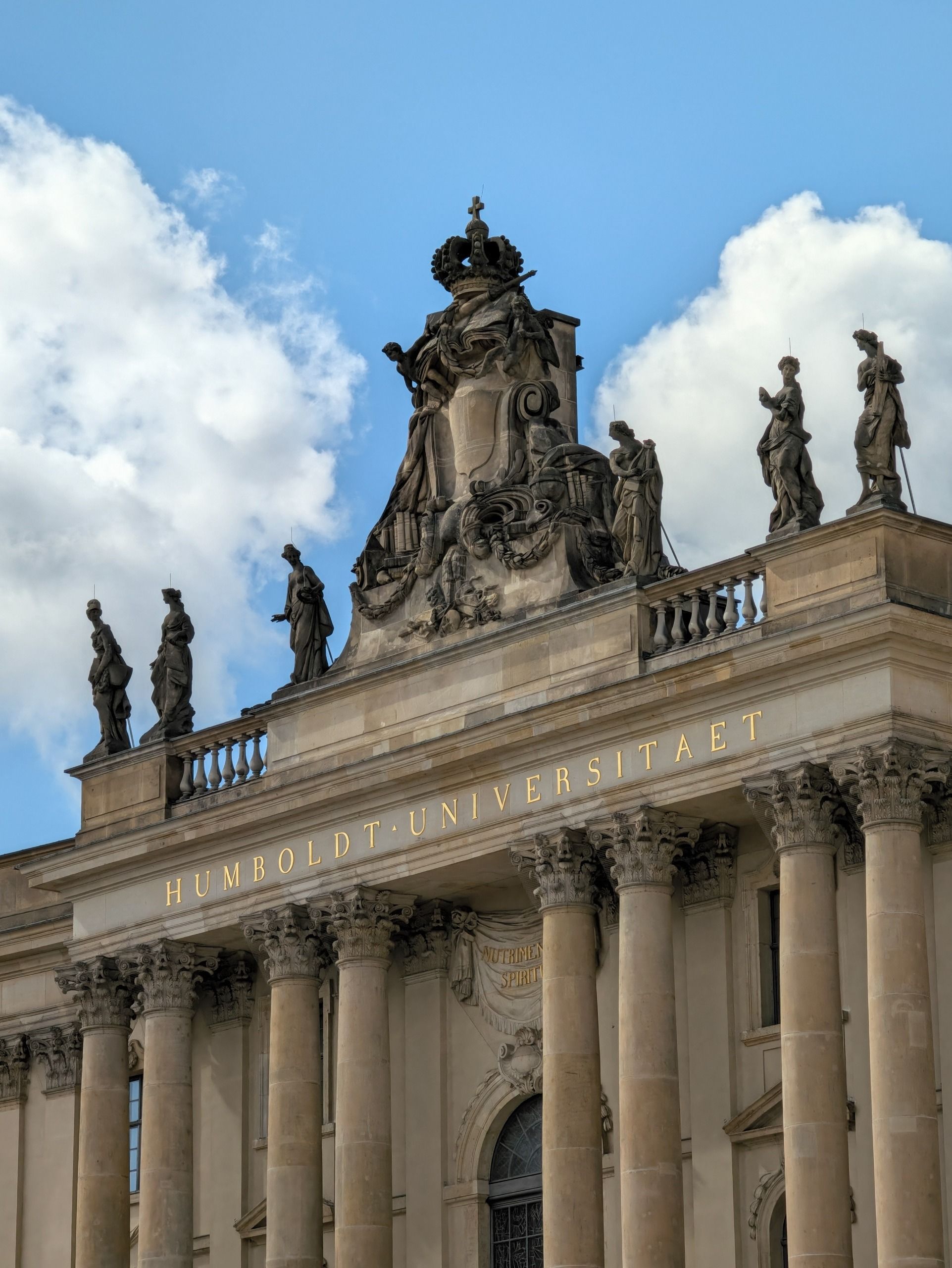 Ornate facade of Humboldt University in Berlin with stone columns, rooftop statues and decorative sculptures.