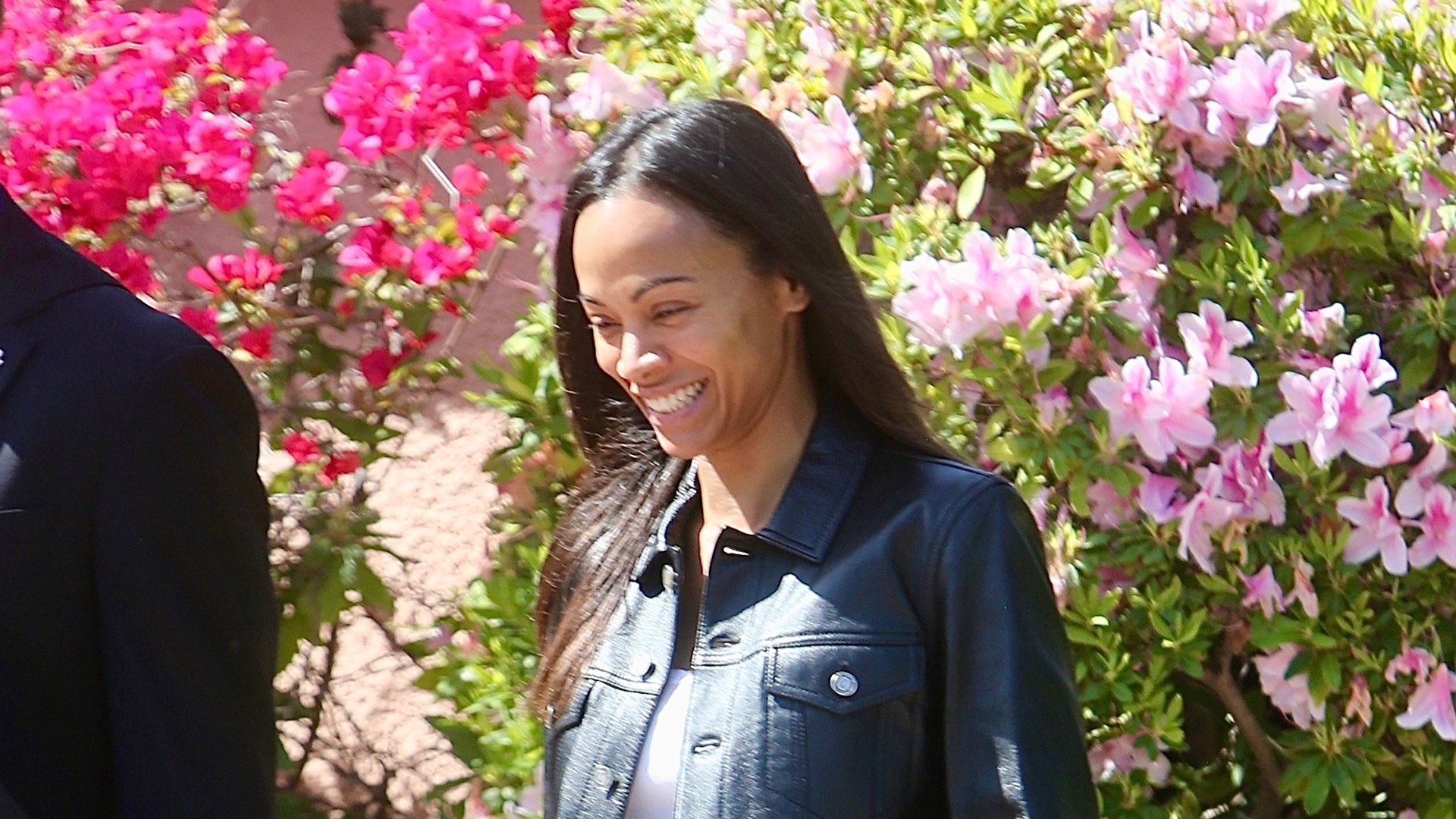 zoe salda&ntilde;a wearing a black leather jacket, blue jeans, and leopard print flats 