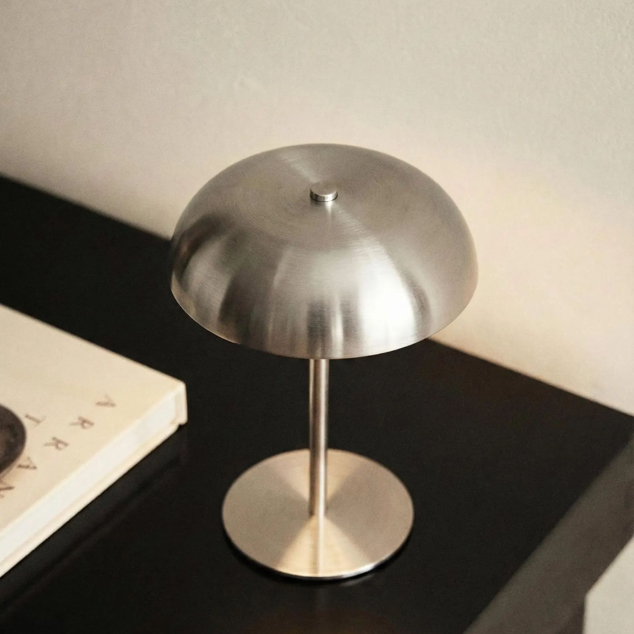 A silver mushroom-shaped table lamp sat on a black shelf.