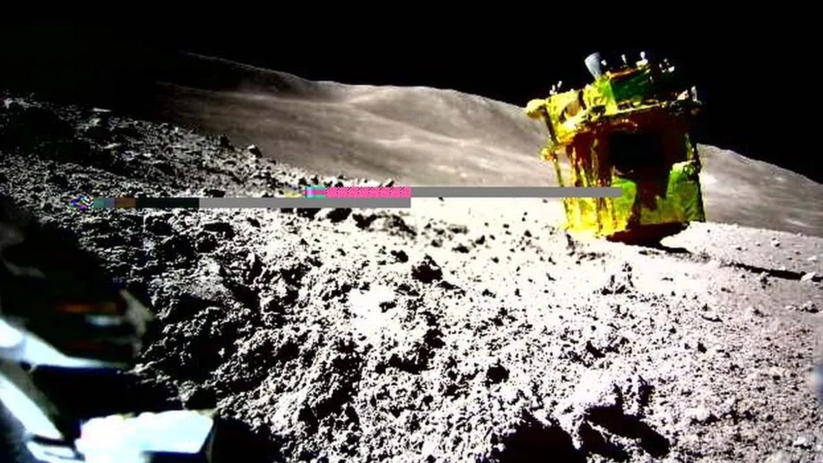 A yellow-colored spacecraft is upside down on the moon. There&#039;s a digital artifact in the center of the image.