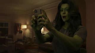Tatiana Maslany's She-Hulk looks surprised as she checks her mobile phone in the character's Disney Plus show
