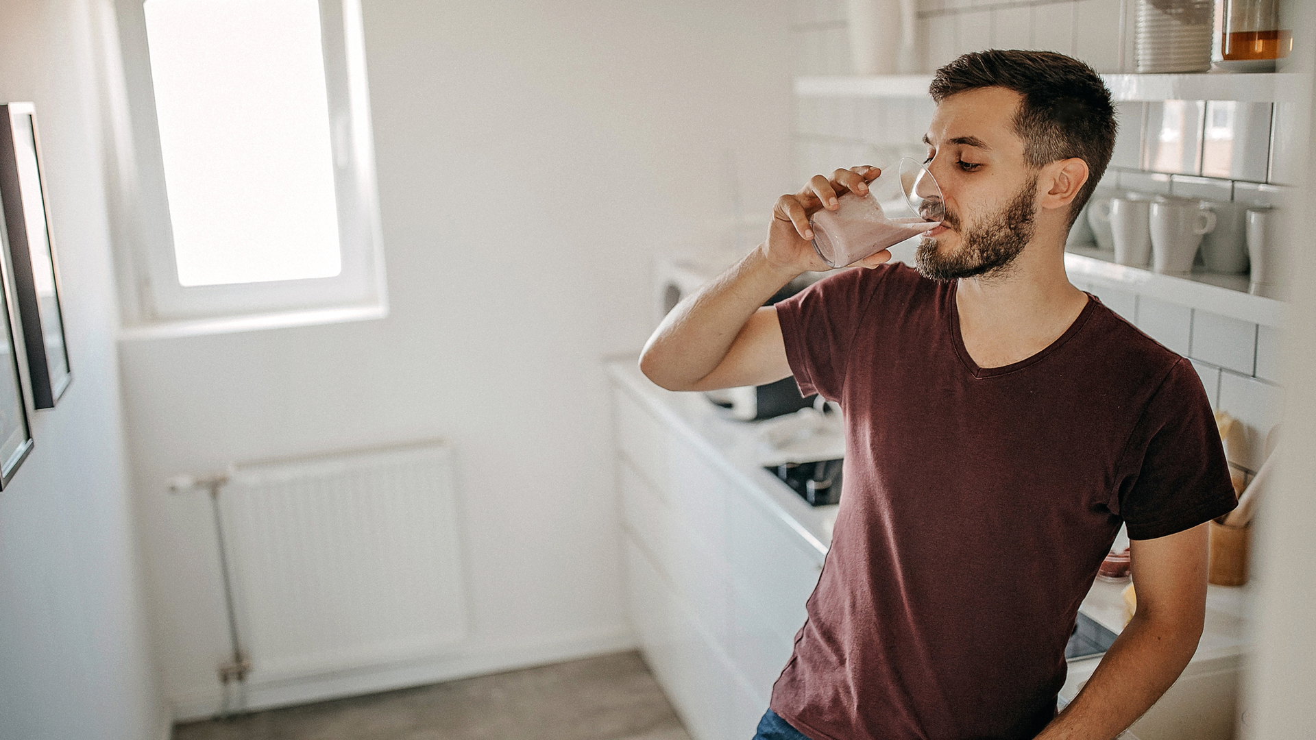 man drinking a meal replacement shake in his kitchen