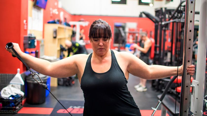 Woman using cable machine to perform lateral raise shoulder exercise