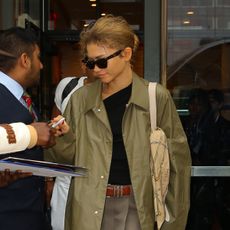 Zendaya signing an autograph wearing a trench coat