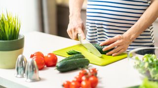 pregnant woman chopping vegetables