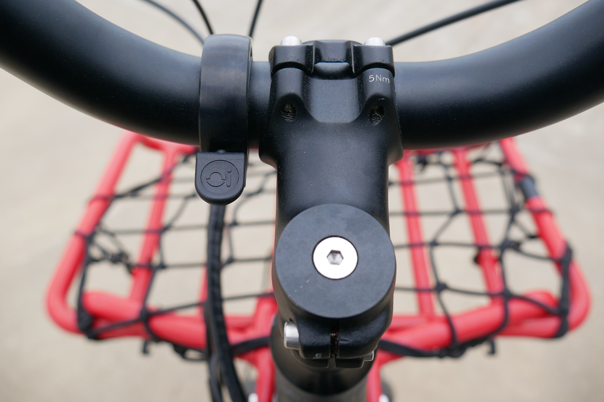 A knog bell mounted next to the teh stem of a Benno RemiDemi XL against the backdrop of a concrete skatepark