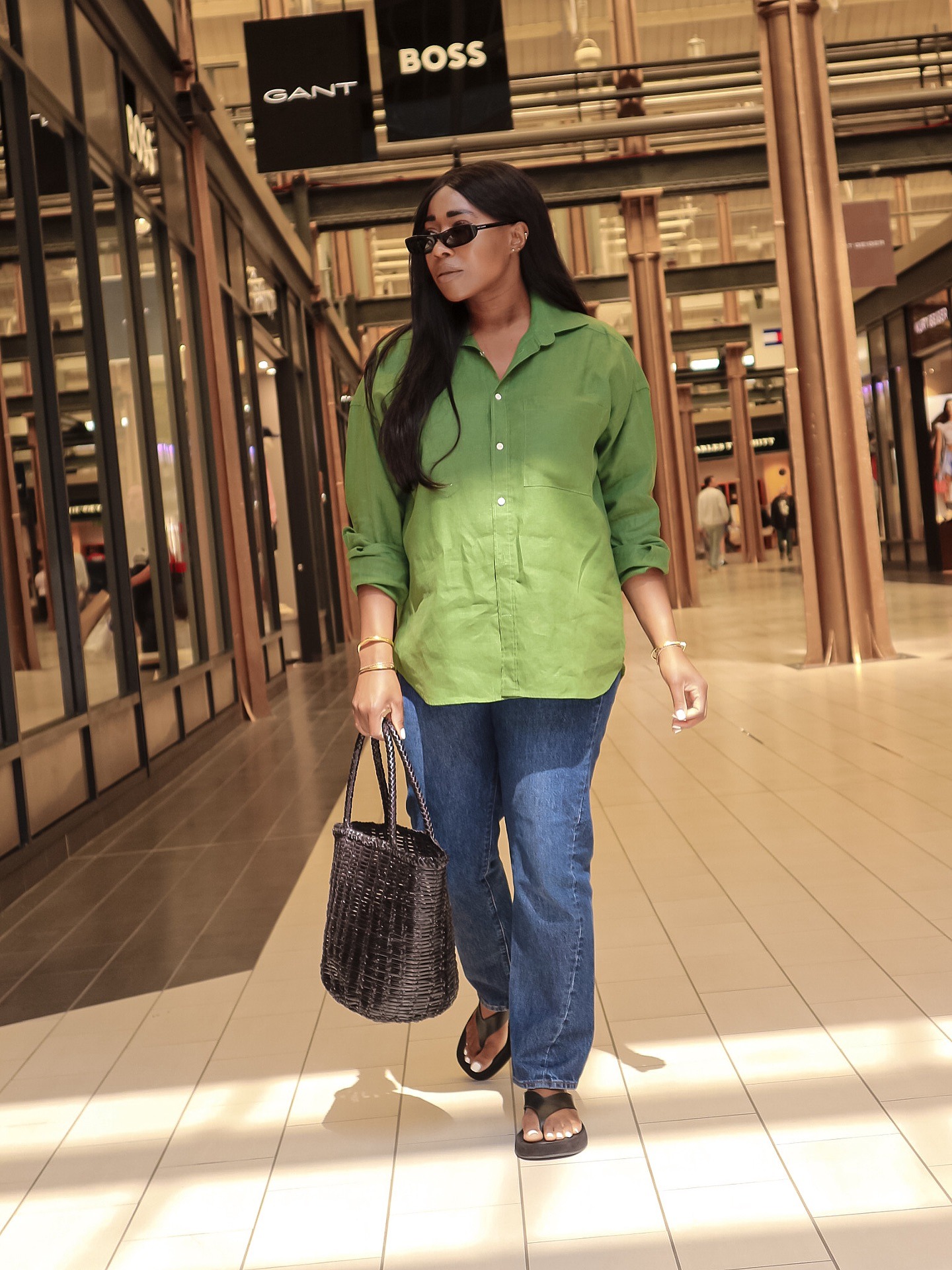 Woman wears green linen shirt, blue jeans and flip flops