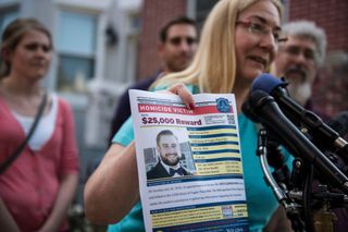 Mary Rich holding up a poster of her son Seth Rich asking for information