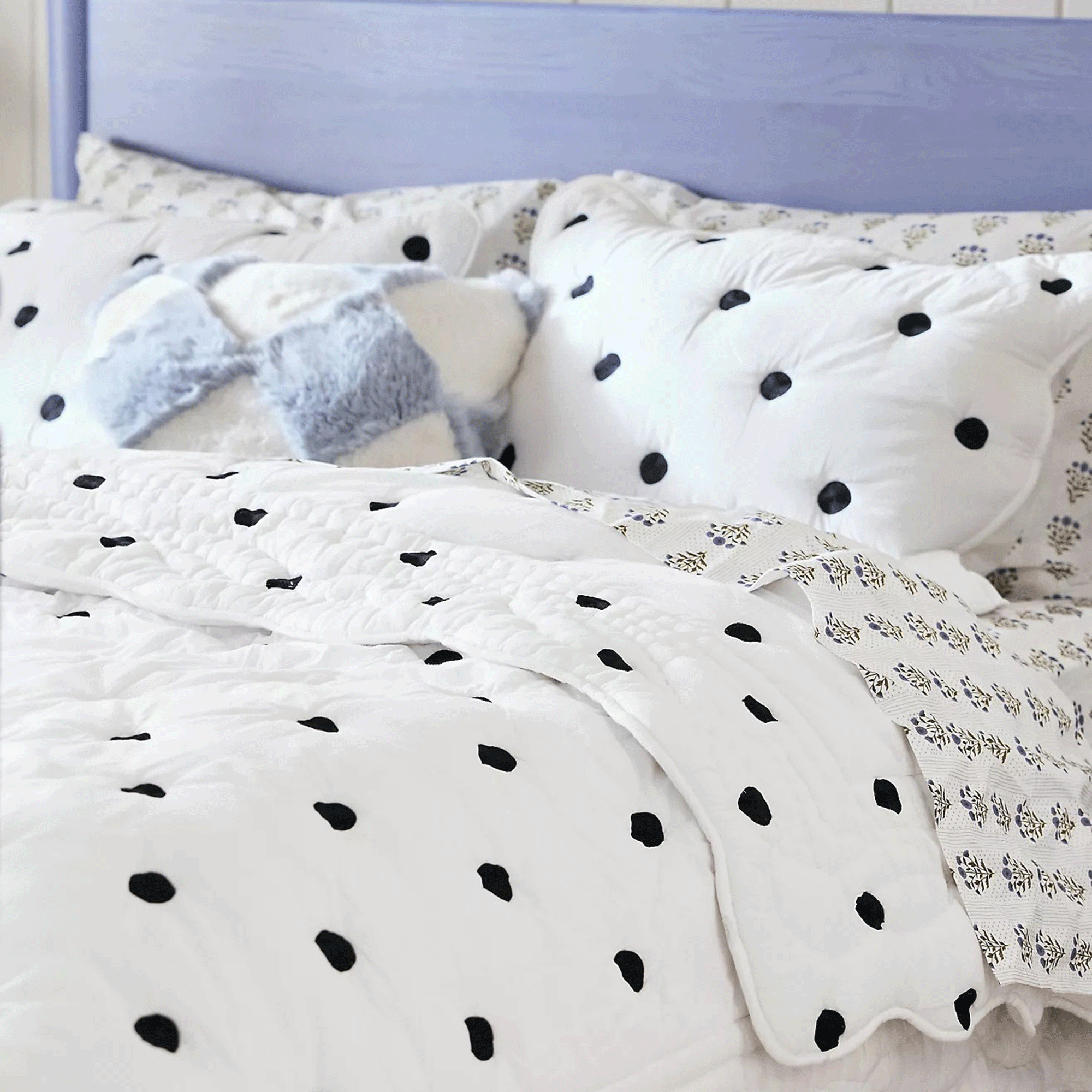 Polka dot bed throw on a bed with matching cushions in black and white