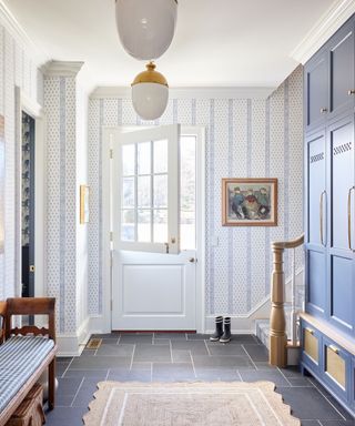 Entryway with white dutch doors, glass pendant lights, blue cupboards and striped wallpaper and bench