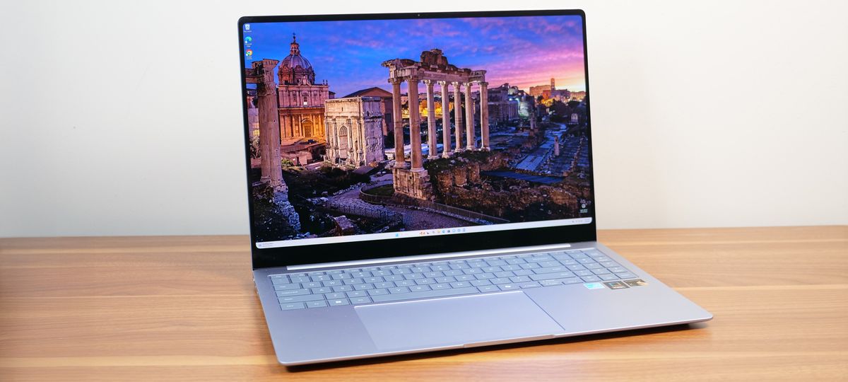 Samsung Galaxy Book 4 Edge angled on a wooden table with a sunset image on the display.