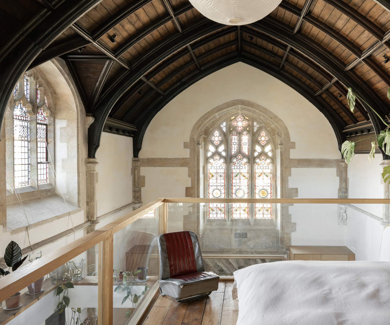 Top of the mezzanine with stained glass window to the front and left-hand side and a bed on the level