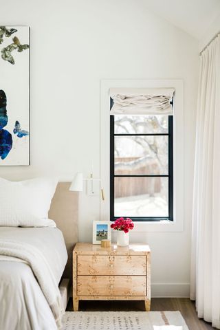 A bright bedroom with sconce lighting installed above the bedside table