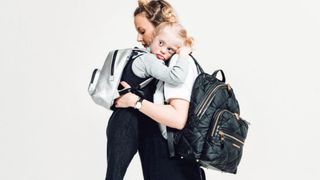 Mum and child hugging wearing satchel bags as part of our best baby shower gifts round up