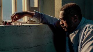 John Luther (Idris Elba) messing with some figures on a windowsill in Luther: The Fallen Sun