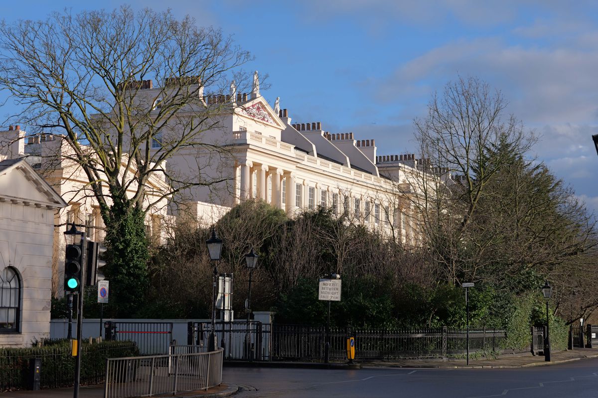 Sun hitting some large white houses rising up above trees