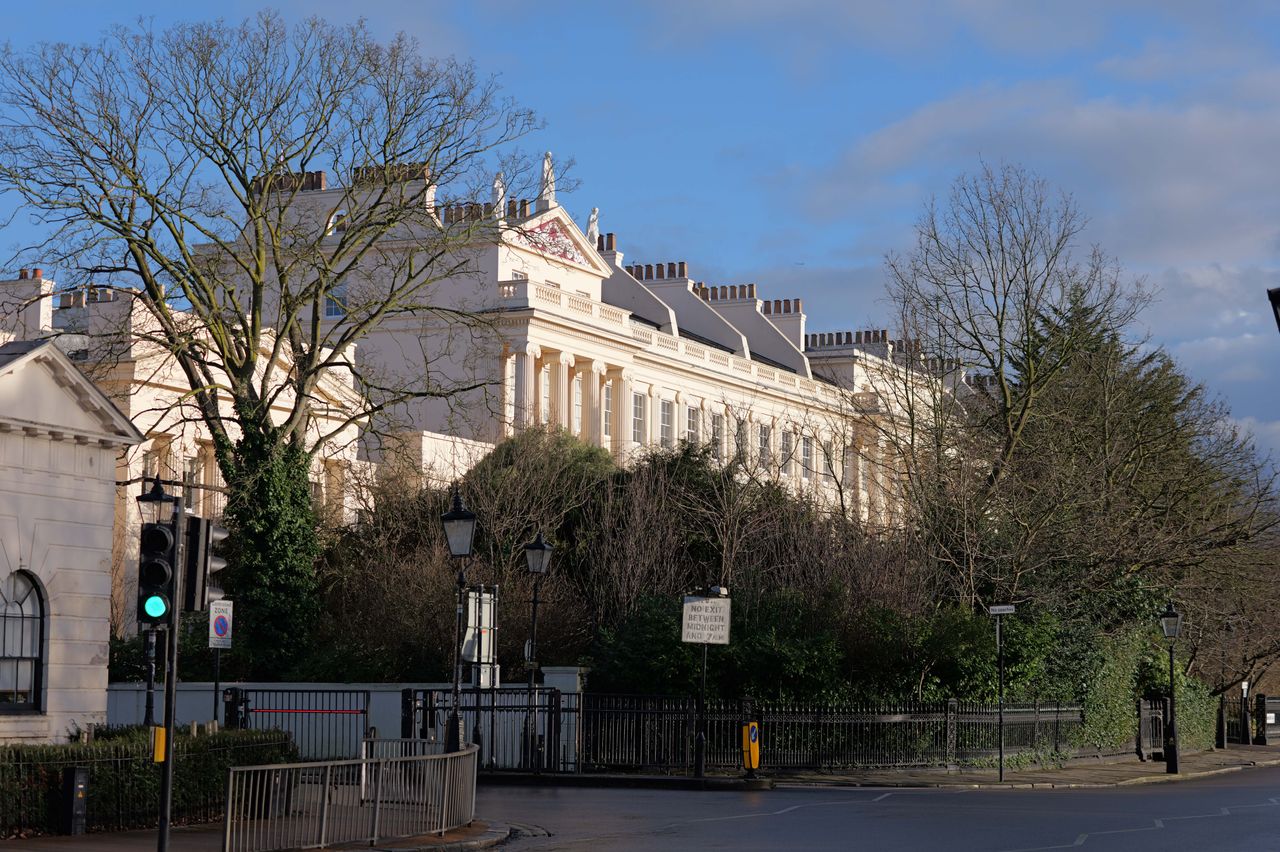 Sun hitting some large white houses rising up above trees