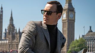 Michael Fassbender leans to the side while standing in front of Big Ben in Black Bag.