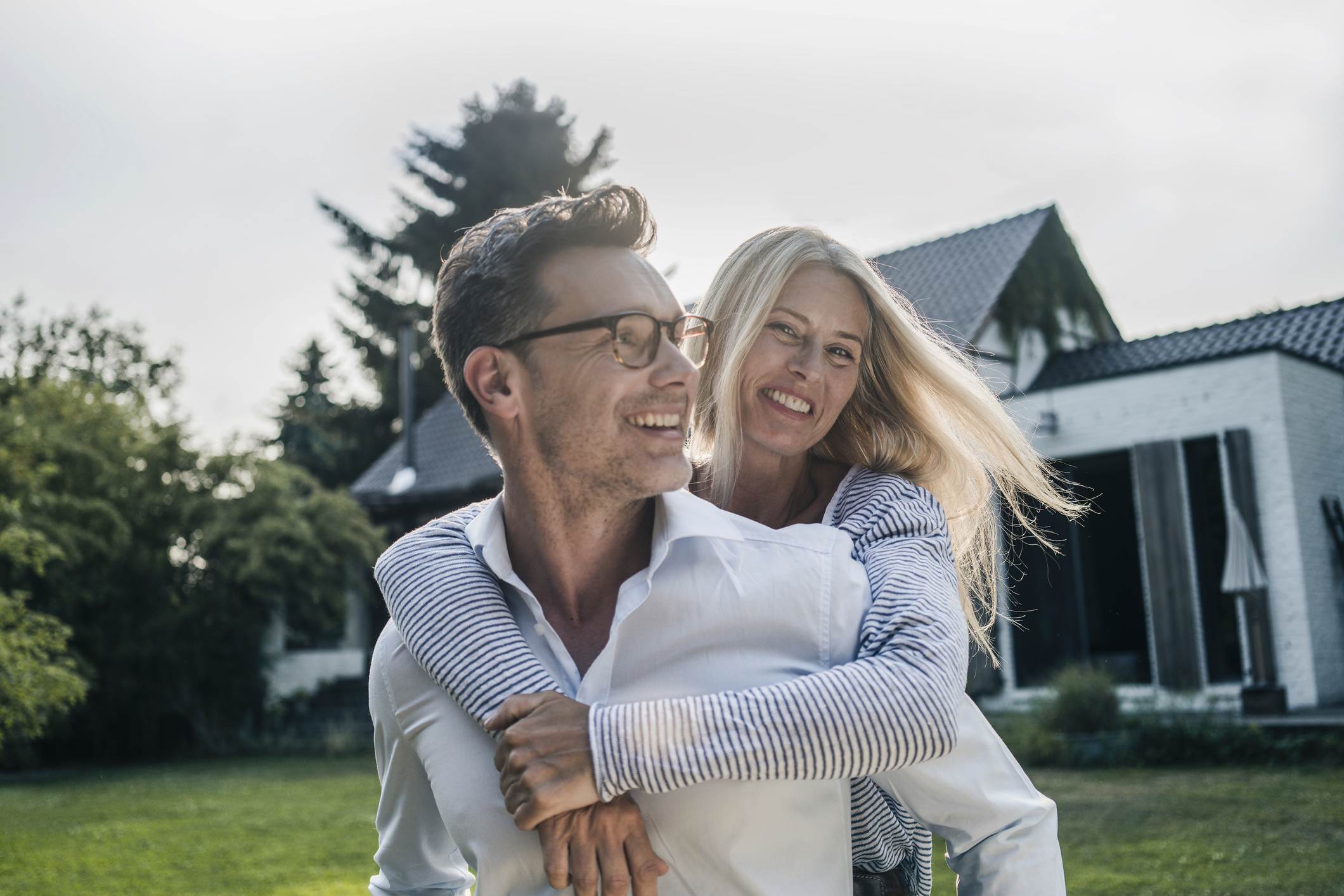 Happy couple embracing in the garden of their country house. They have a high net worth.