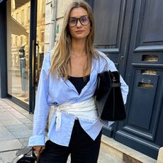 anne wears blue-button down shirt wrapped with white scarf paired with black pants