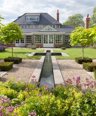 Long garden ideas with a water feature, rectangular gravel and low box hedges.