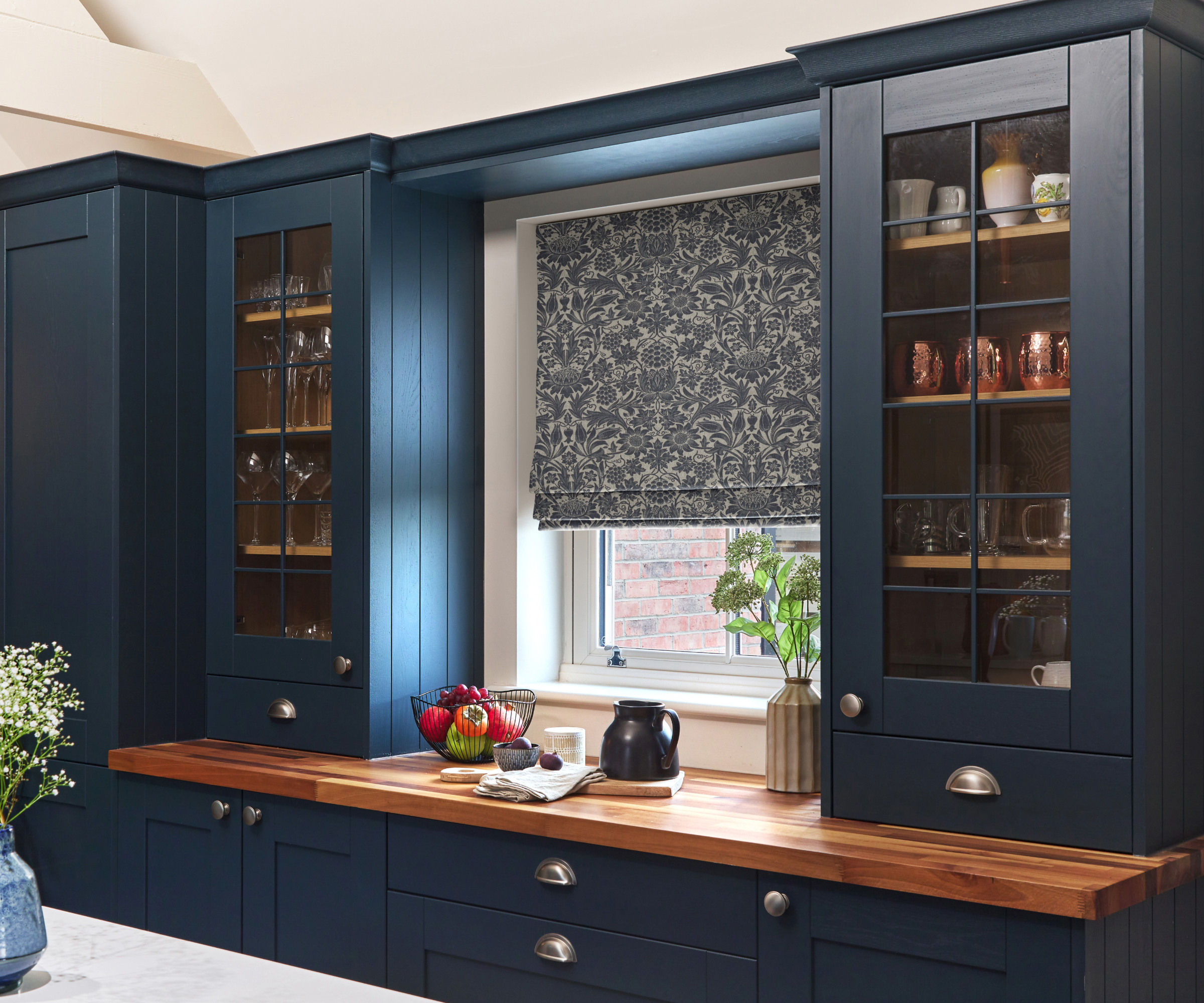 Kitchen with dark blue cabinets and a white and blue patterned blind