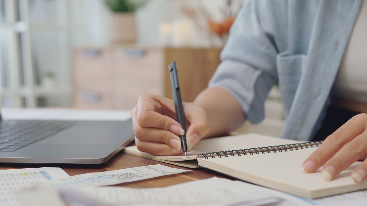 A woman tracks spending in a spiral notebook. 