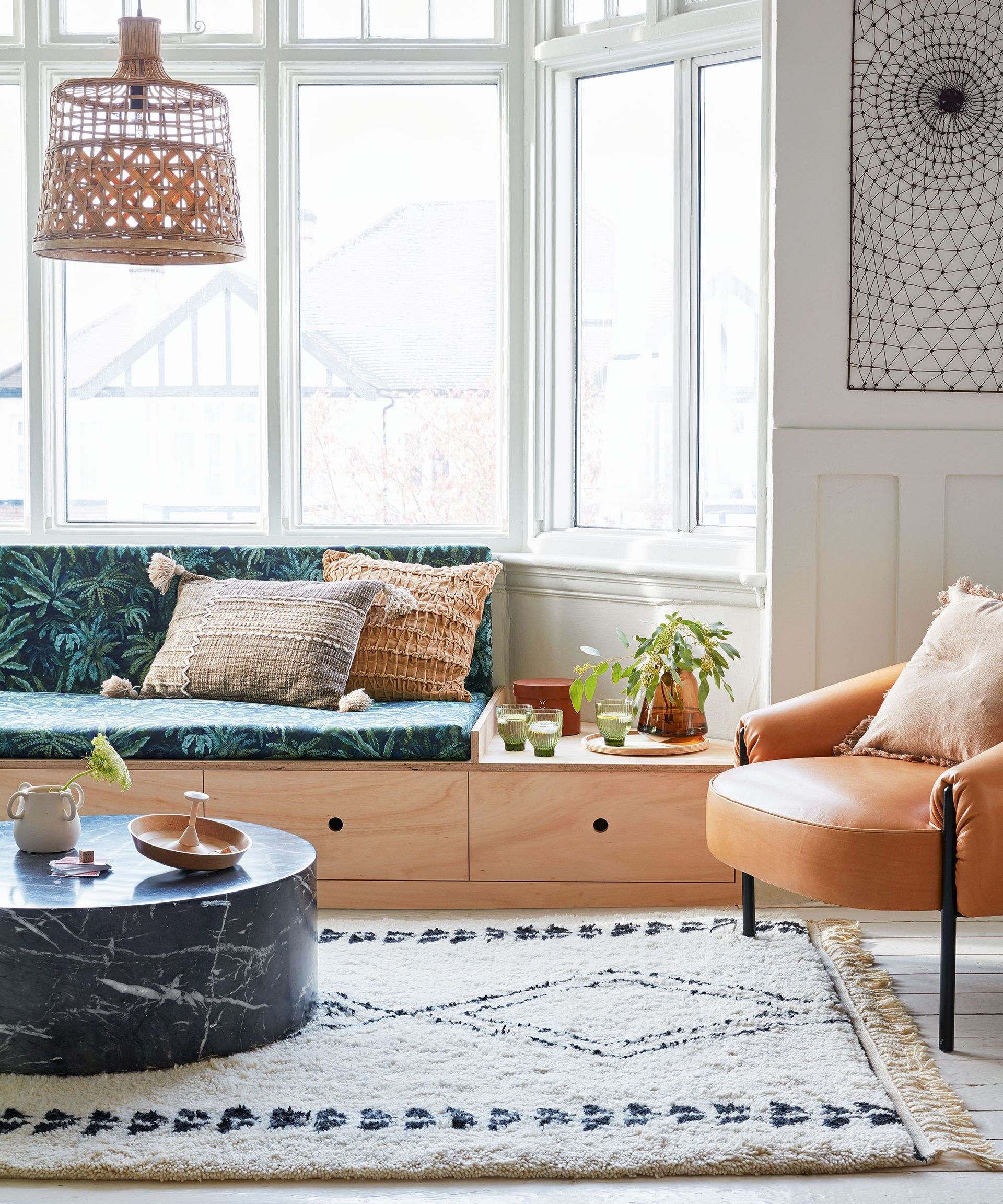 White living room with built in wooden storage underneath seating in bay window