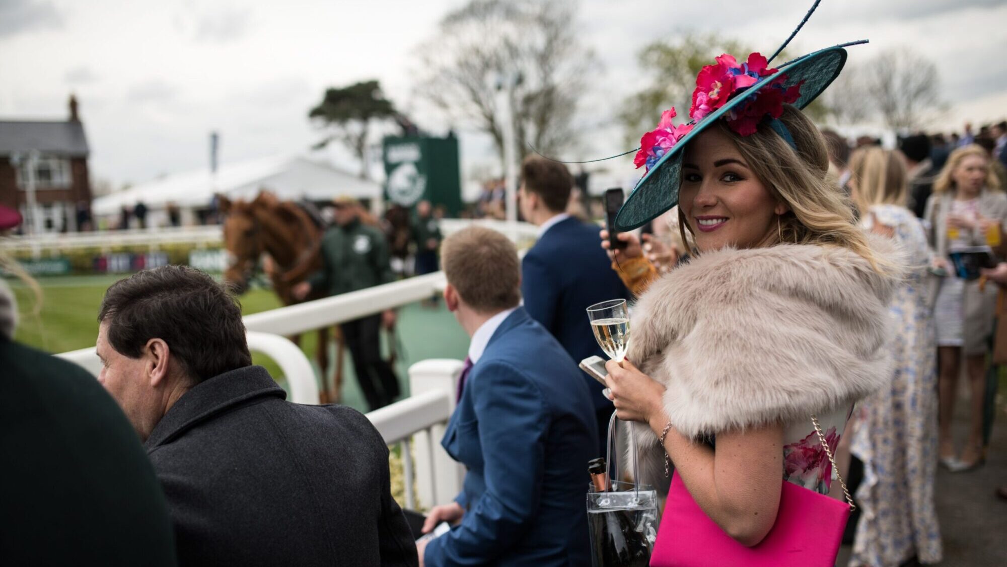 Racegoers watch horses in the parade ring on Ladies Day, the second day of the Grand National Festival