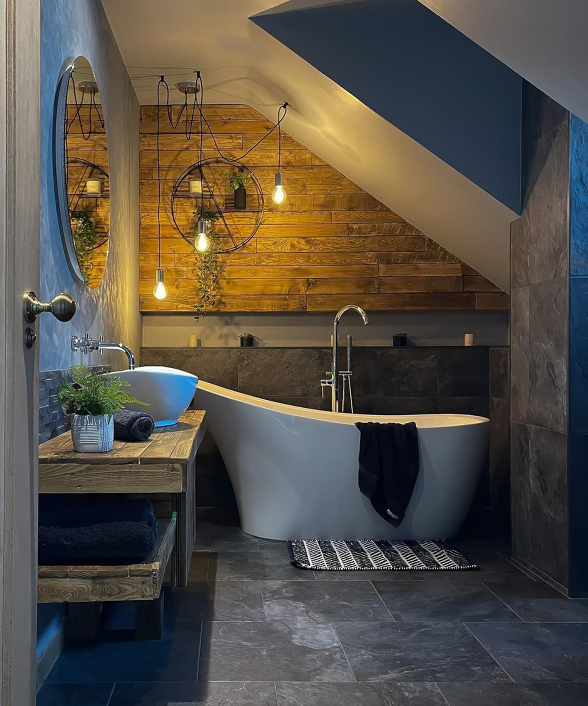 A small bathroom idea with freestanding bath, vanity unit made from old pallets and round shelf in alcove