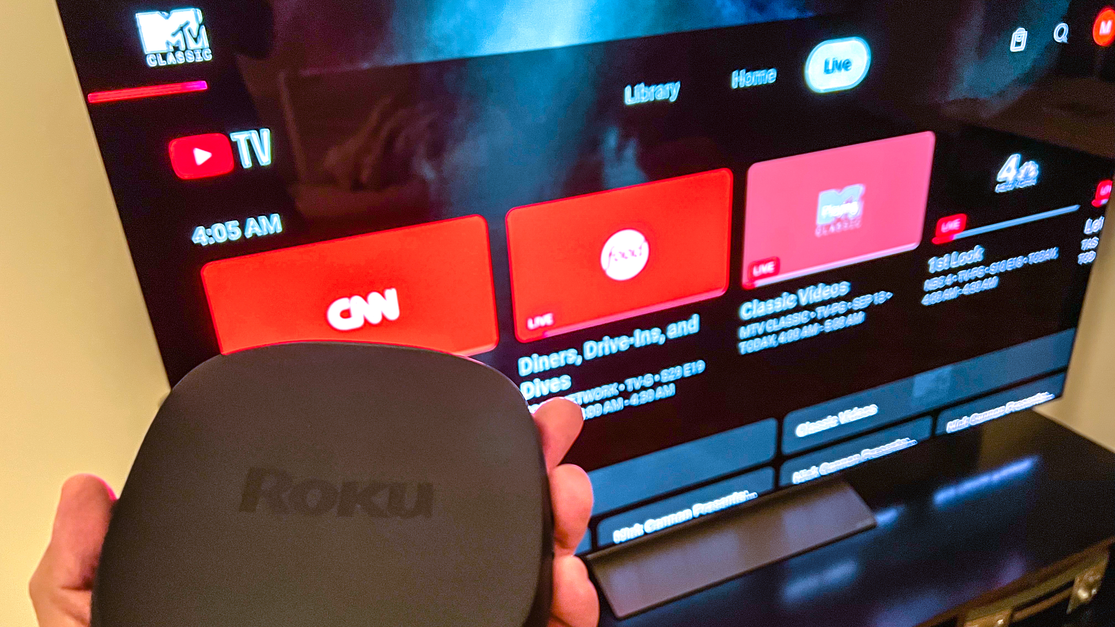 Roku Ultra held in front of TV displaying YouTube TV