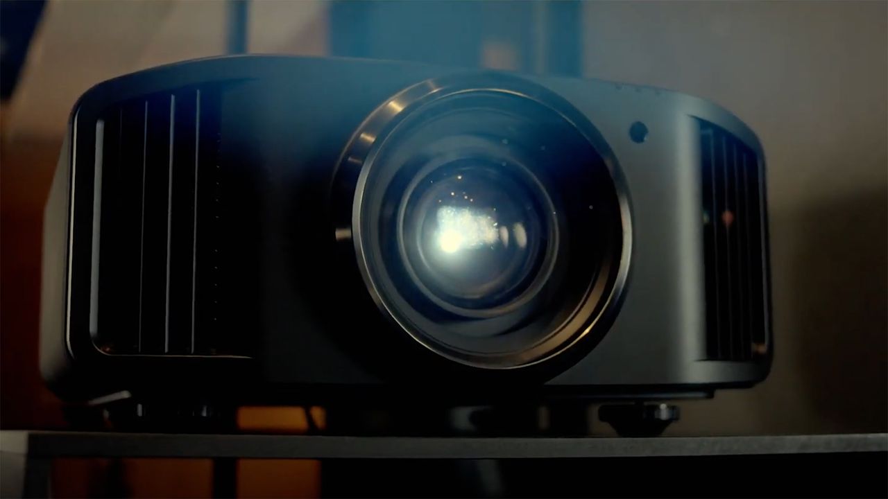 JVC DLA-NZ8 projector on a table, with light shining from it