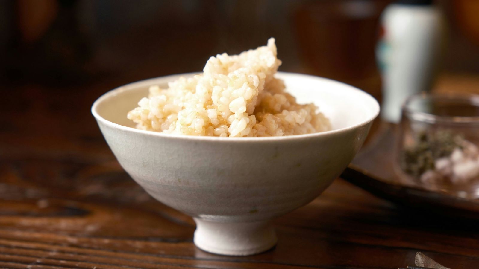 Grey ceramic bowl of fluffy sushi rice, on a dark wooden table