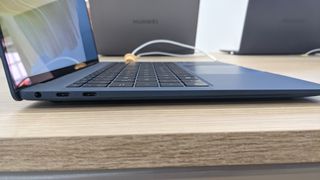 Huawei MateBook X Pro (2022) on a wooden desk with charger plugged in.