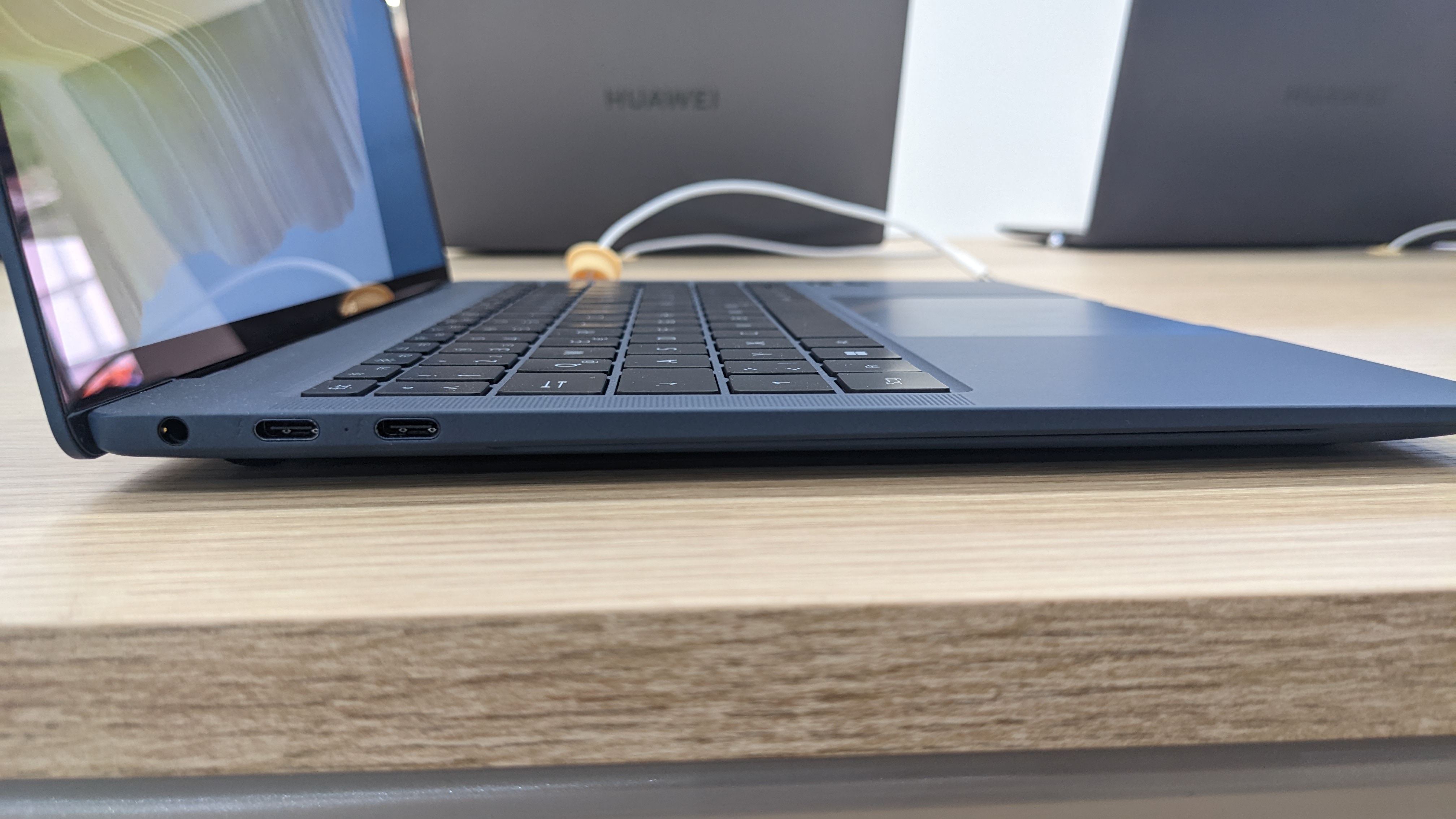 Huawei MateBook X Pro (2022) em uma mesa de madeira com um carregador conectado.