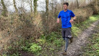 A man wearing Saxx Roast Master Mid-Weight Tights runs along a woody trail