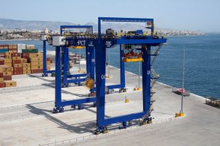 A blue shipping container crane on the dockside.