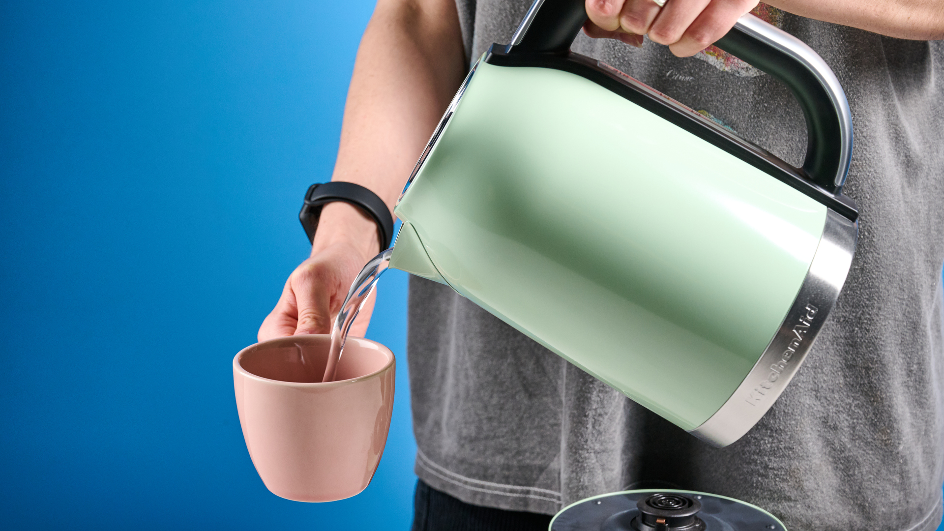 the kitchenaid 1.7L kettle in pistachio photographed on a white marble counter with a blue background