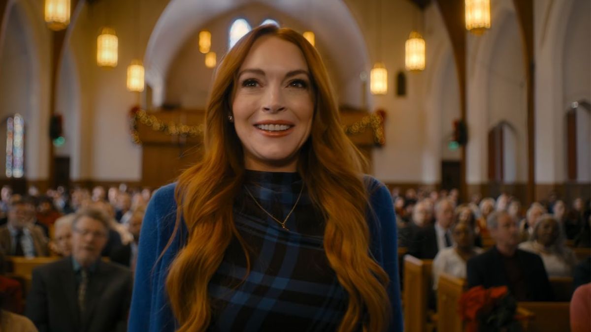 Lindsay Lohan dress in blue plaid, trying her best to smile as she walks through the aisle of a church in Our Little Secret